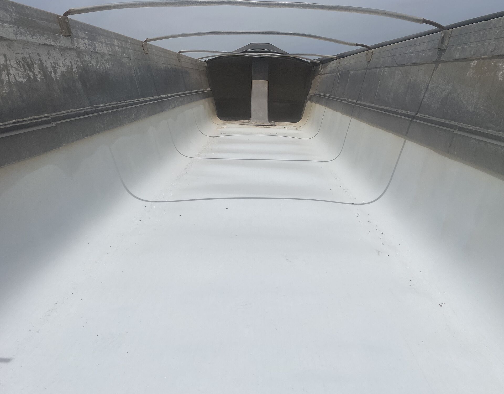 White poly liner in the back of a dump truck and flexible nylon tarp bows over the dump truck body